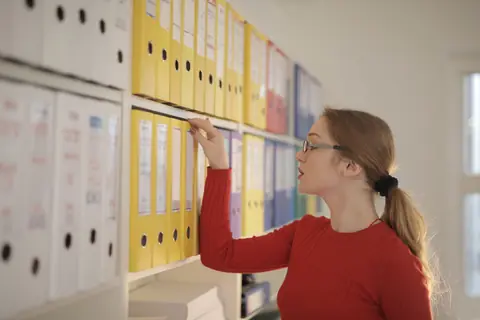 Une professionnelle cherche un dossier dans des classeurs d'archives