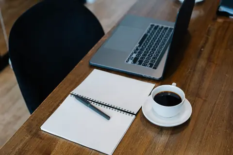 Ordinateur portable, carnet ouvert et tasse de café sur un bureau en bois