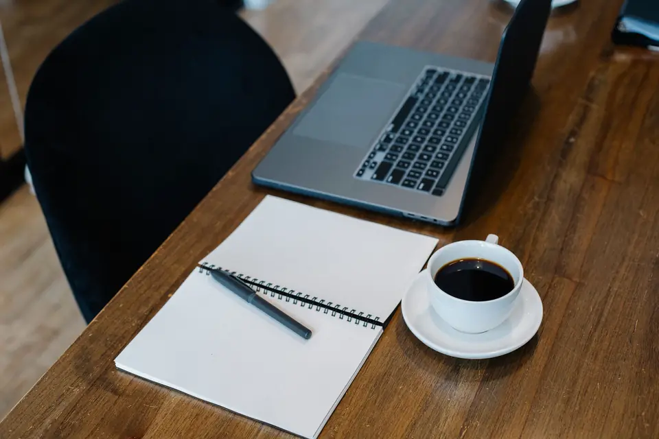 Ordinateur portable, carnet ouvert et tasse de café sur un bureau en bois