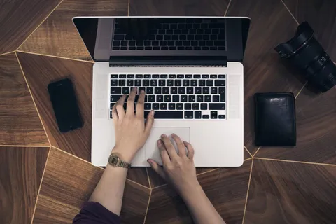 Mains sur le clavier d'un ordinateur portable, sur un bureau
