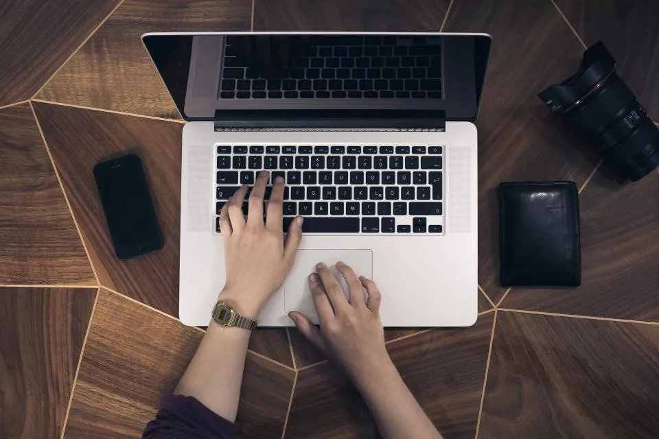 Mains sur le clavier d'un ordinateur portable, sur un bureau