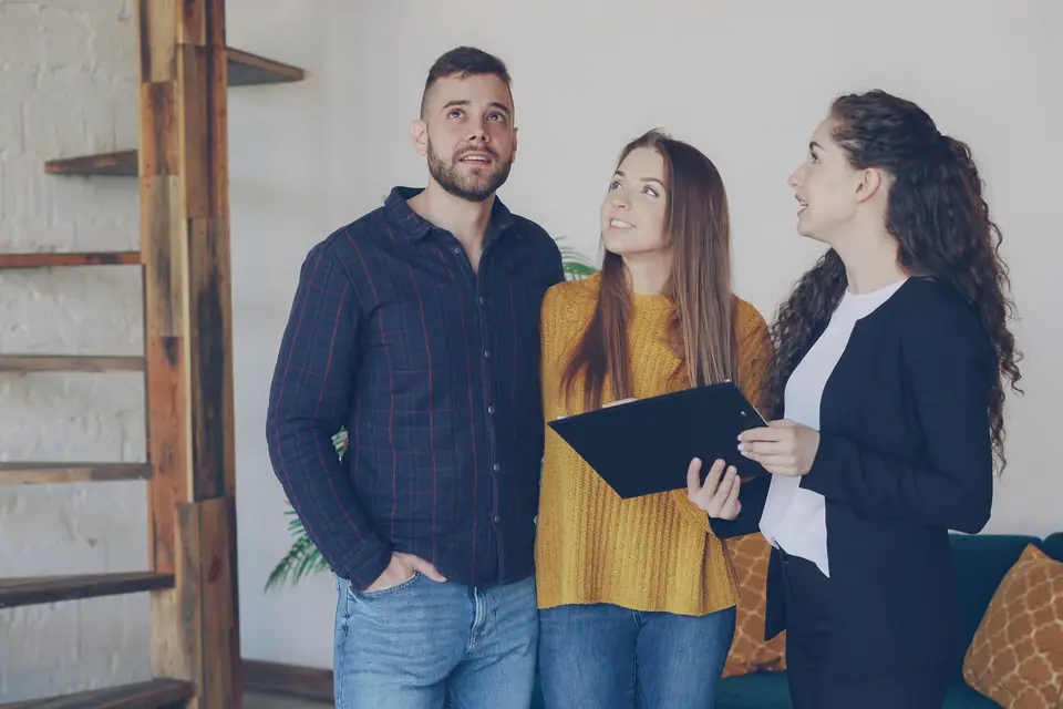 Une agente immobilière, dossier en main, accompagne un couple pendant une visite