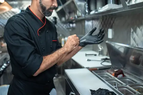 Un cuisinier enfile des gants dans la cuisine d'un restaurant