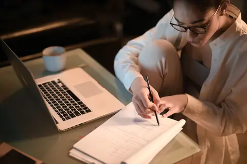 Une professionnelle prend des notes le soir devant son ordinateur