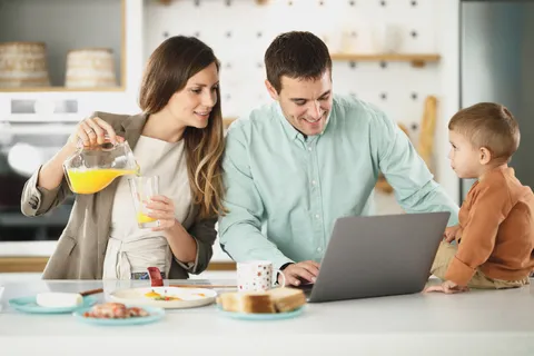 Une famille prépare un projet autour d'un ordinateur portable dans sa cuisine