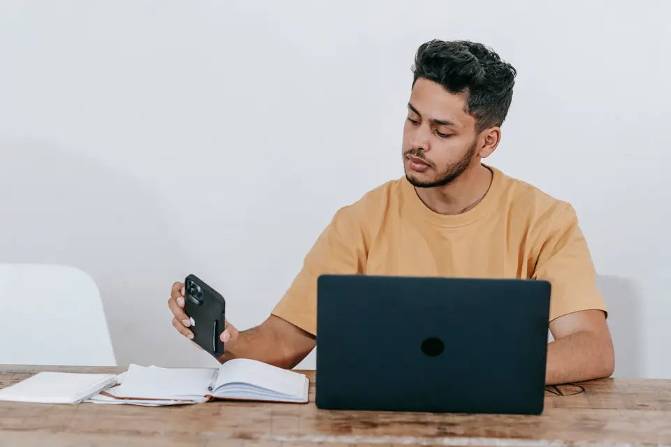 Un professionnel consulte son téléphone à côté de son ordinateur portable