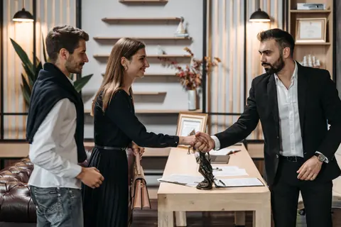 Un conseiller serre la main d'un couple de clients dans son agence