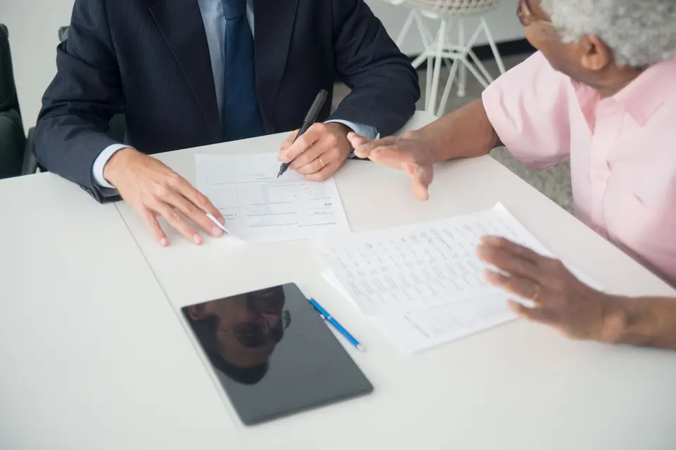 Un conseiller et un client relisent un contrat sur une table