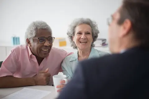 Un couple de retraités échange en souriant avec son conseiller