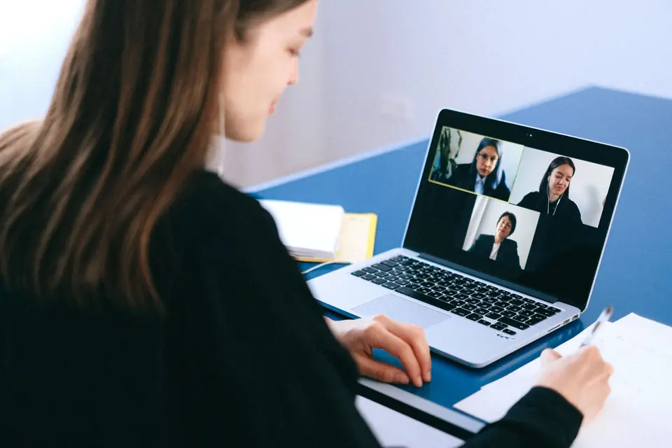 Une professionnelle participe à une visioconférence et prend des notes